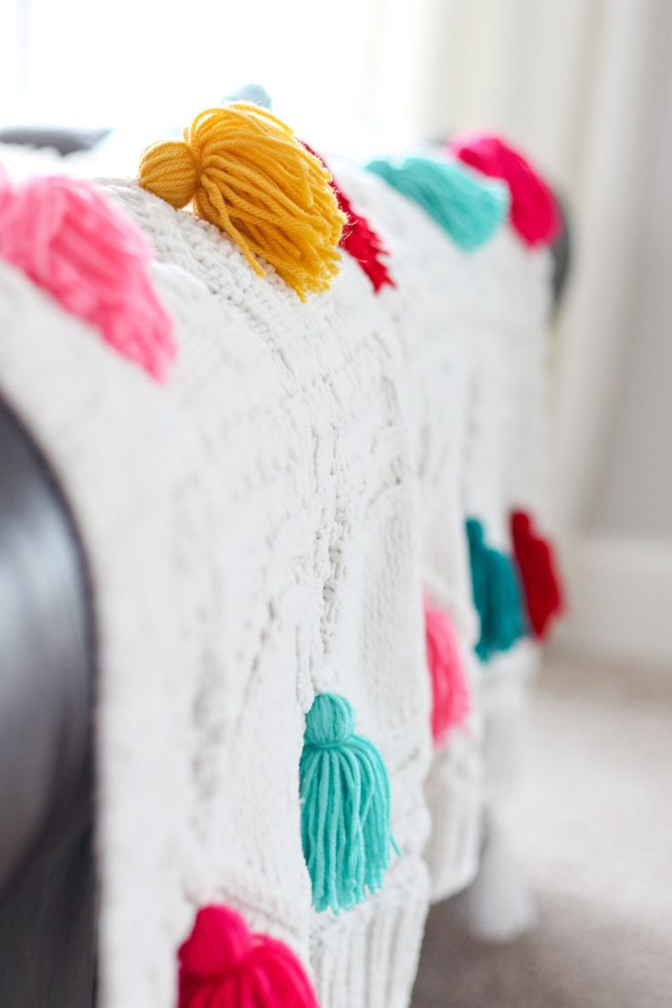 a crocheted blanket with tassels on it sitting on top of a couch