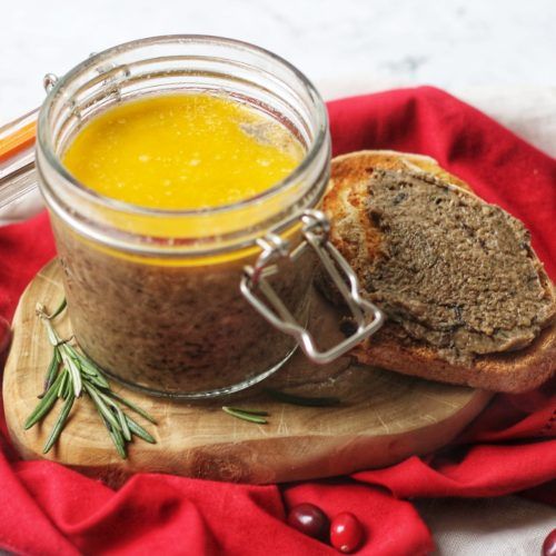 a jar filled with mustard sitting on top of a wooden cutting board next to bread