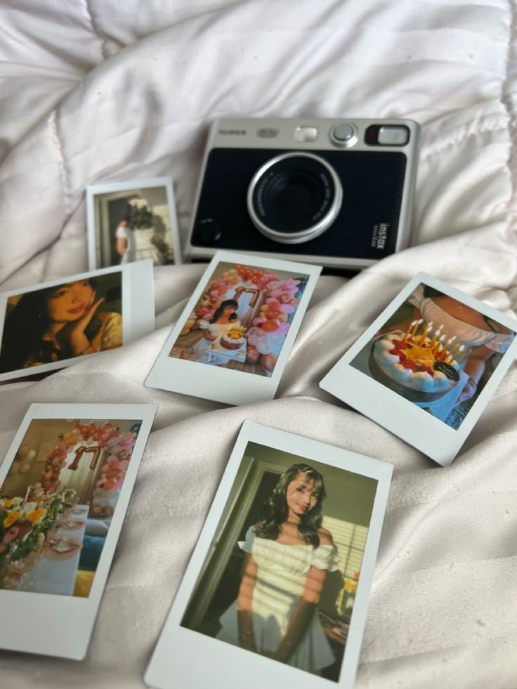 several polaroid pictures are arranged on a bed with a camera and other items in front of them