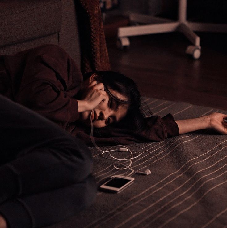 a woman is laying on the floor with her head in her hands and two cell phones