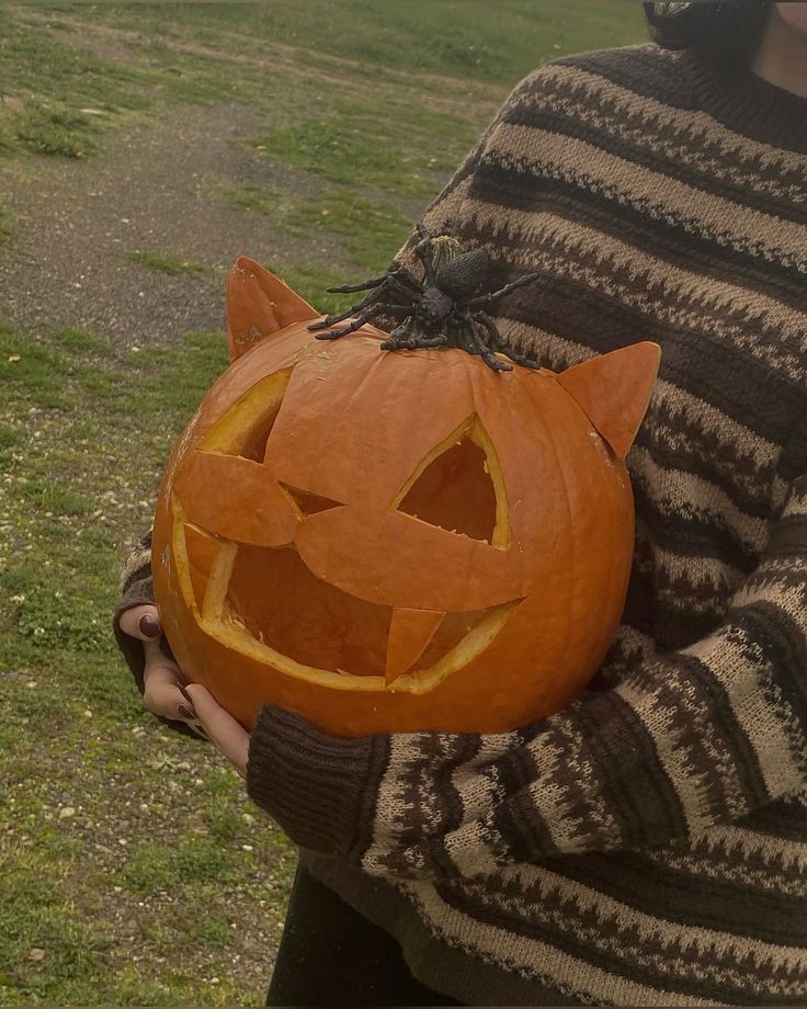 a person holding a carved pumpkin with a cat on it