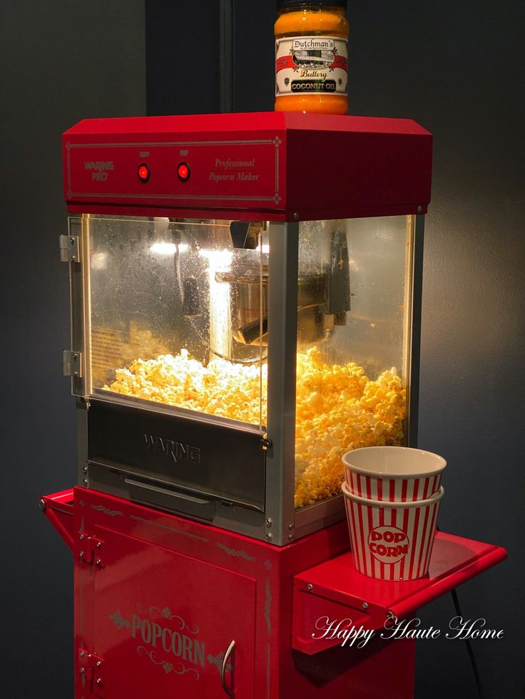 a popcorn machine sitting on top of a red tray next to a bowl of food