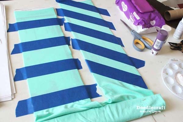 the table is covered with blue and green striped fabric next to crafting supplies on it