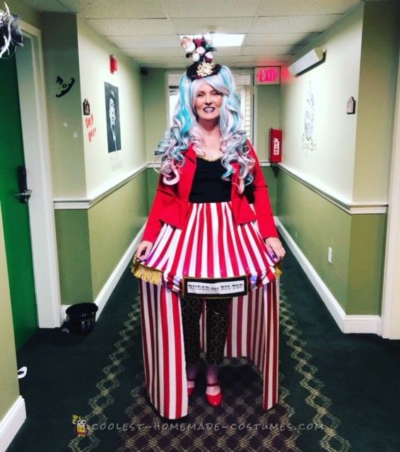 a woman dressed as a circus clown standing in a hallway with green walls and carpet