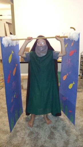 a man is standing in front of two blue boards with fish on them and one has his arms above his head