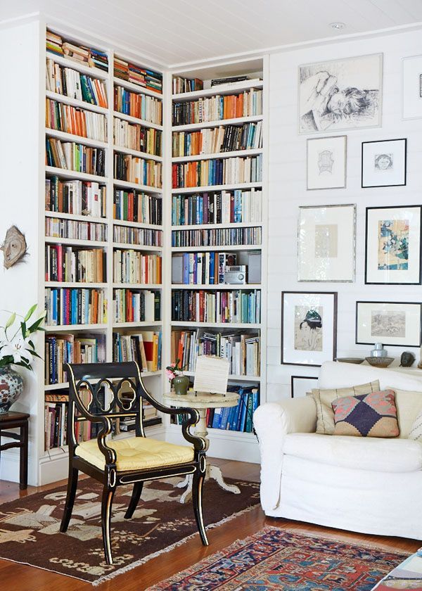 a living room filled with furniture and lots of bookshelves covered in pictures on the wall