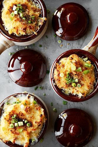 four small bowls filled with food on top of a table next to utensils