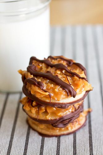 three cookies with chocolate drizzled on them next to a glass of milk