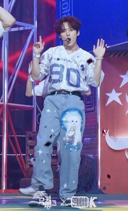 a young man standing on top of a stage with his hands up in the air