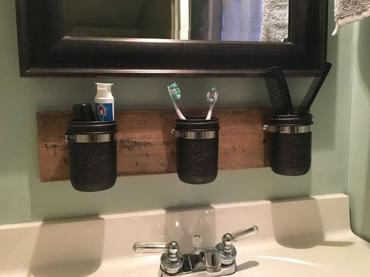 three toothbrushes and two toothpaste holders are hanging on the wall above a bathroom sink