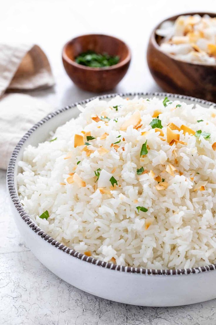 white rice in a bowl with two bowls behind it