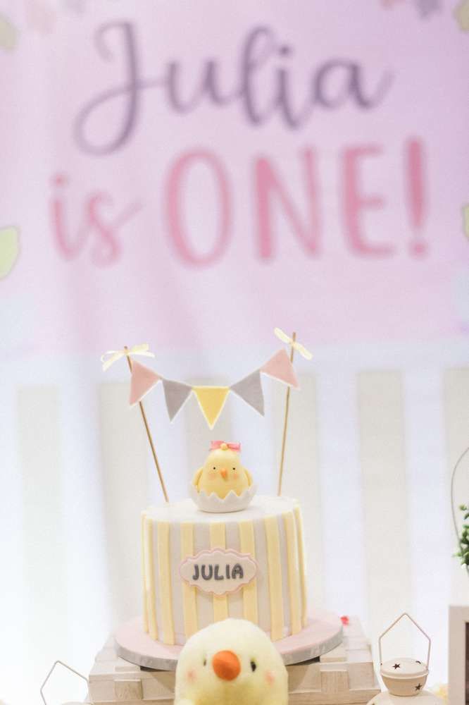 a baby shower cake with a rubber ducky on the top and bunting banner in the background