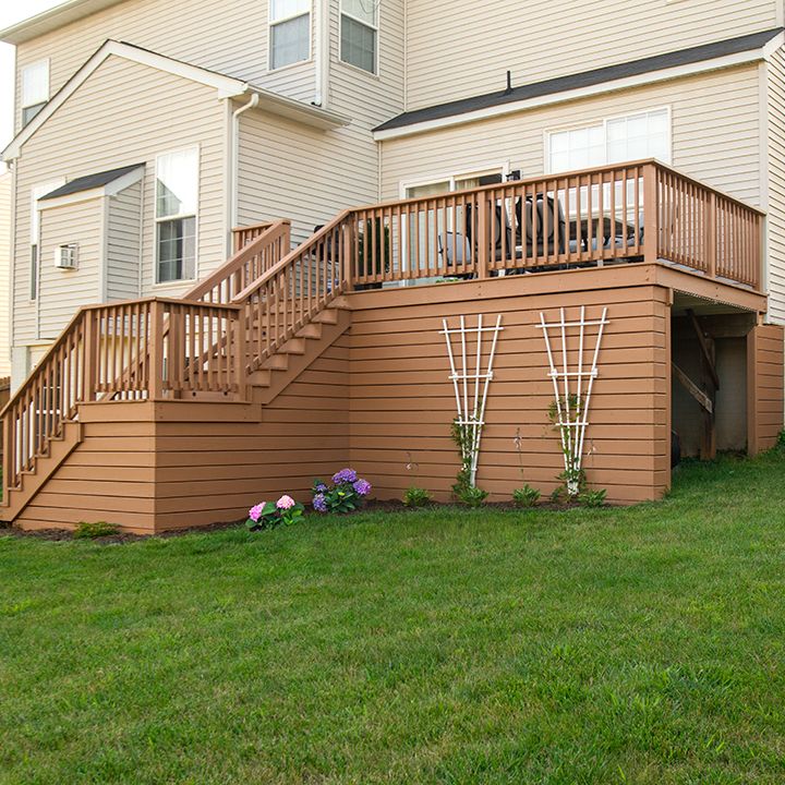 a house with stairs leading up to the second floor and another building in the background