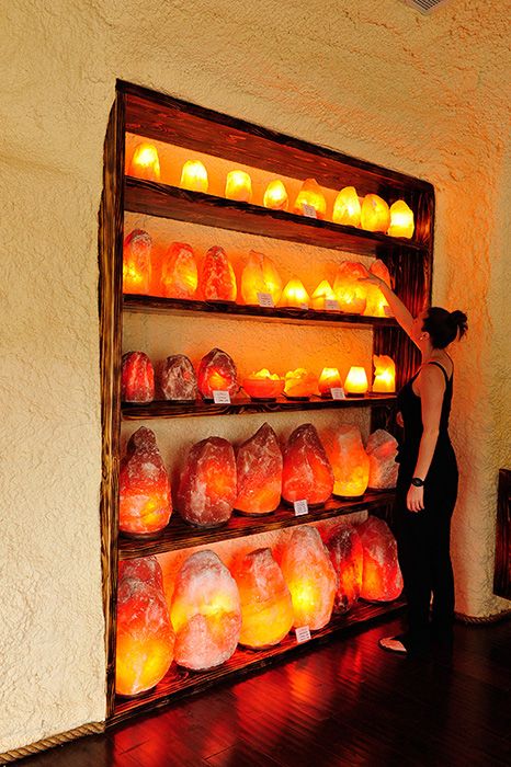 a woman standing in front of a shelf filled with lit candles and bags on top of it