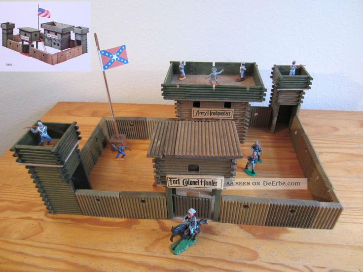 some toy soldiers in front of a wooden building with a flag on the roof and two flags