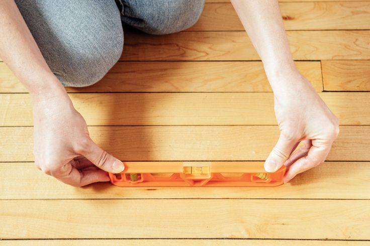 a person sitting on the floor with an orange object in their hand and two hands holding it