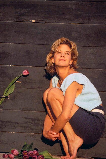 a woman kneeling on the ground next to flowers