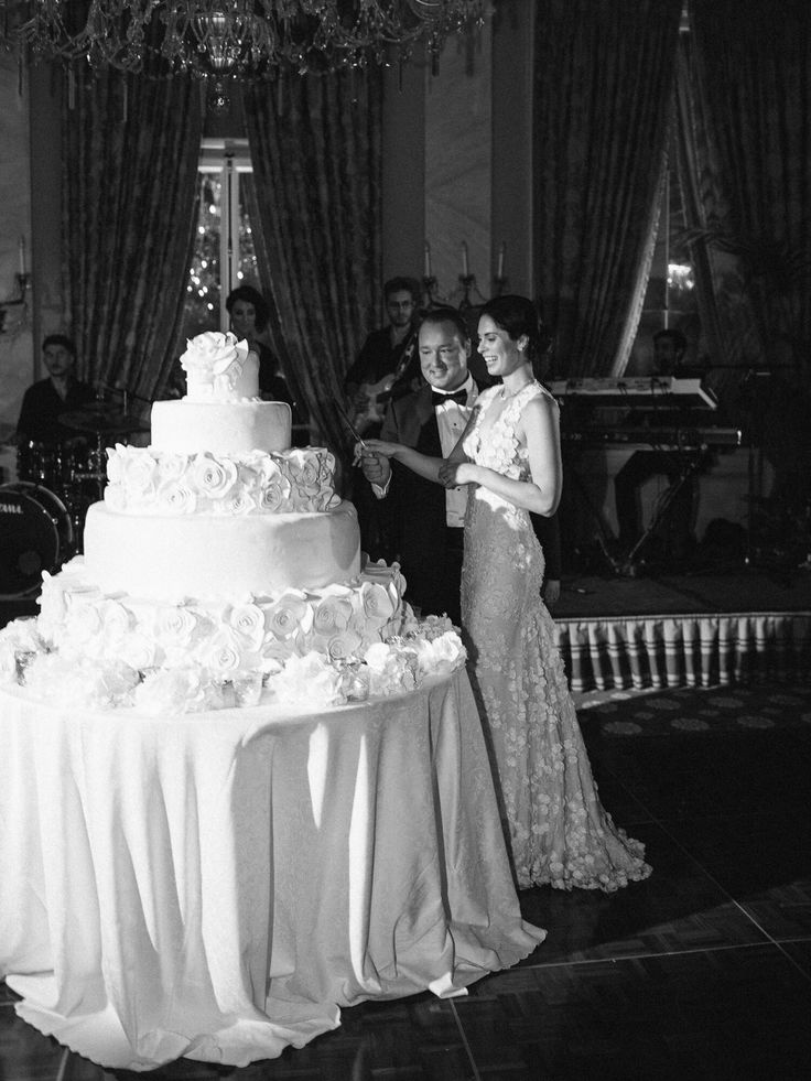 two people standing next to a wedding cake