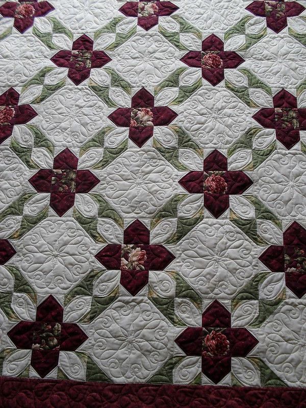 a quilted table topper with red and white flowers