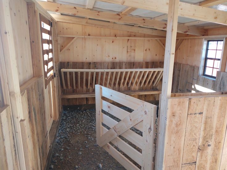 the inside of a horse barn with wooden stalls