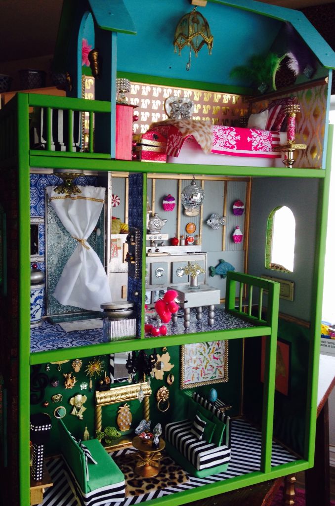 a green doll house with lots of furniture and accessories on it's shelves in a living room