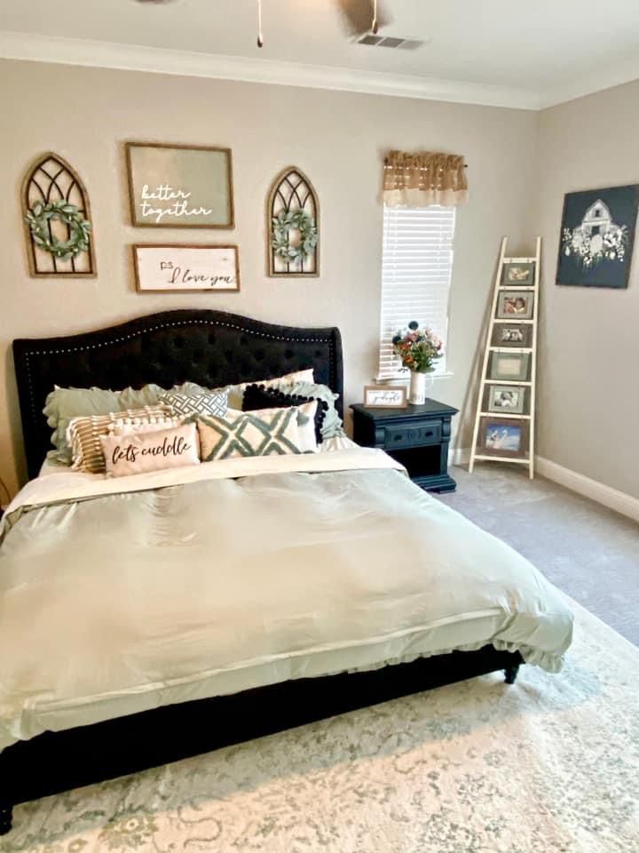 a large bed in a bedroom next to a window with pictures on the wall above it