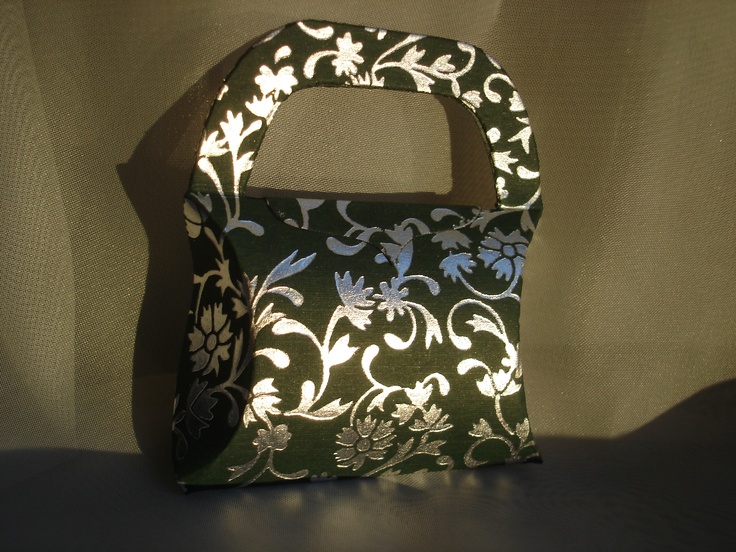 a small purse is sitting on a white tablecloth with black and white floral designs