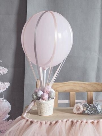 a pink balloon sitting on top of a table next to a vase filled with flowers