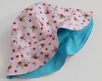 a pink and blue hat with strawberries on it sitting on top of a white table