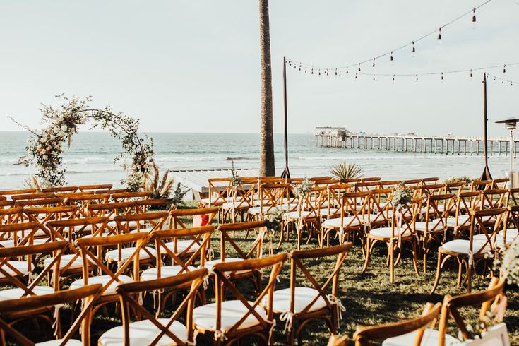 rows of wooden chairs set up in front of the ocean