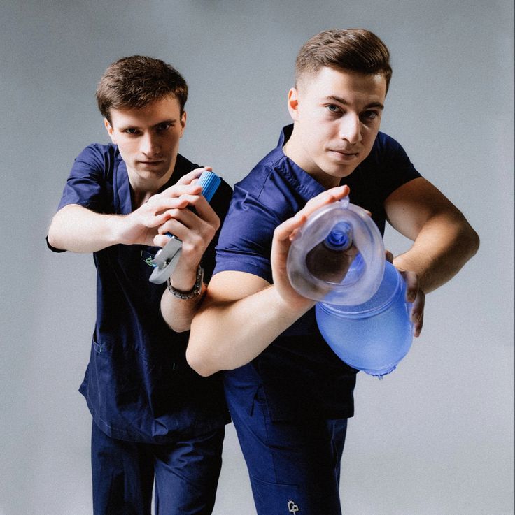 two young men are holding water bottles and looking at the same thing in front of them