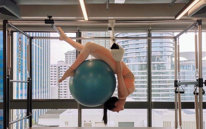 a woman is doing aerial exercises on an exercise ball in the middle of a room