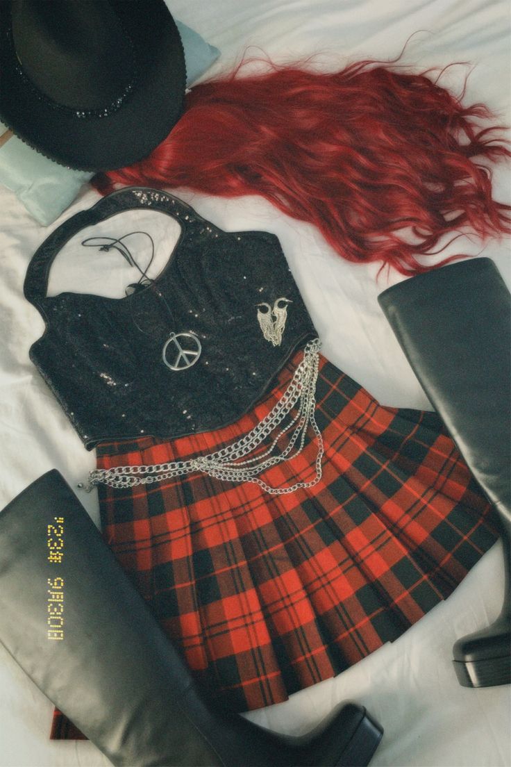 a woman's outfit and boots are laid out on a white sheet with red hair