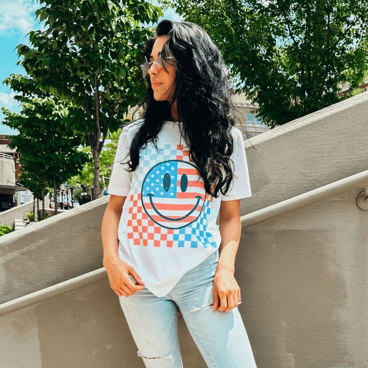 How CUTE! Red, white and blue + smiley + checkerboard = perfect! Part of our Patriotic Collection. Printed with ink on our white soft blend unisex fitted tee. Model is 5'6 wearing a medium. Playful White T-shirt With Smiley Face, Playful White T-shirt For Everyday, Playful T-shirt For 4th Of July With Crew Neck, Playful Crew Neck T-shirt For 4th Of July, Fun White Everyday T-shirt, White Playful T-shirt With Smiley Face, White Smiley Face T-shirt, Playful White T-shirt For 4th Of July, White Graphic Tee With Smiley Face