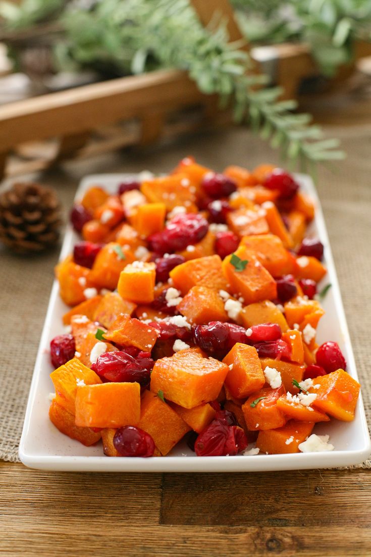 a white plate topped with carrots and cranberries on top of a wooden table