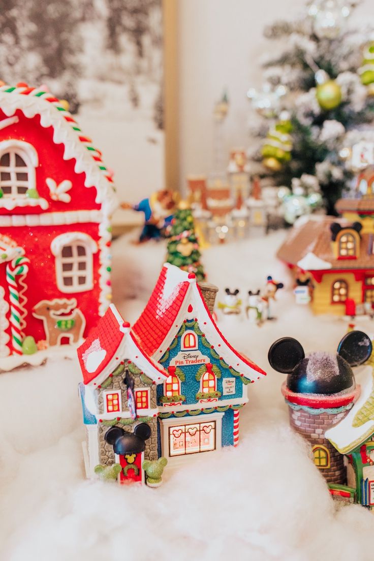 mickey mouse figurines in front of a christmas tree and other disney themed houses