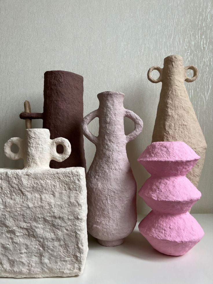 three different colored vases sitting next to each other on a white counter top, one pink and one brown