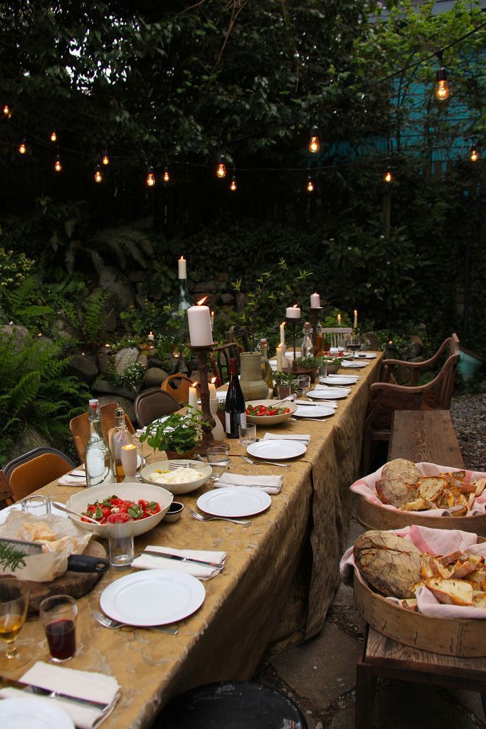 a long table is set up with plates and food for an outdoor dinner in the woods