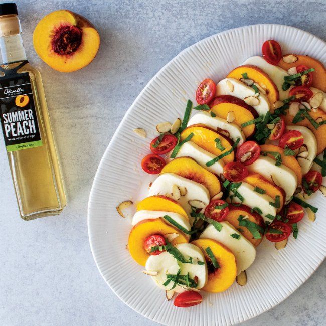 a white plate topped with sliced peaches next to a bottle of sunflower oil