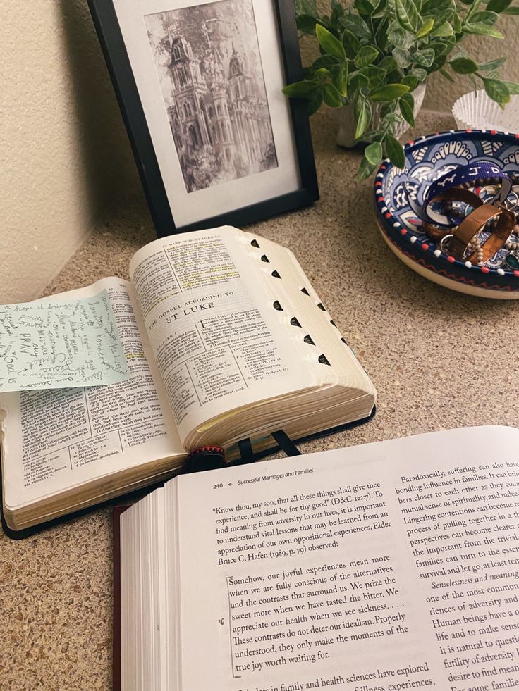 an open book sitting on top of a table next to a vase with flowers in it