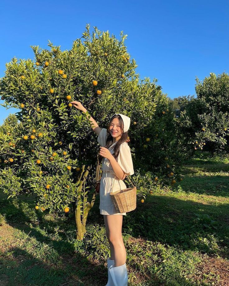 a woman standing next to an orange tree