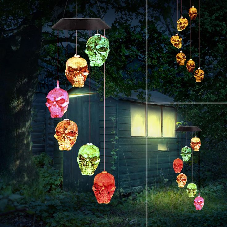 a group of skulls hanging from strings in front of a house with lights on them