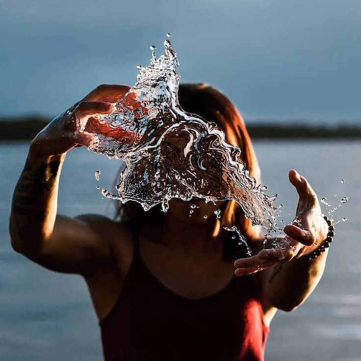 a woman is holding her head in the air with water splashing on her face