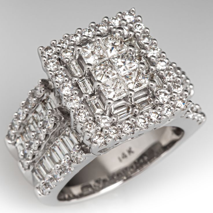 This stunning ring is centered with six (6) invisible/prong set princess cut diamonds surrounded by ten (10) prong set baguette cut diamonds and thirty (30) prong set round, brilliant cut diamonds. The shoulders of the ring each contain ten (10) channel set baguette cut diamonds and fifteen (15) prong set, round diamonds. The ring measures 14.8mm at the top, rises 10.0mm above the finger, tapering to 5.9mm wide and 1.8mm thick at the base of the shank. It is currently a size 6. Rectangular Diamond White Ring With Baguette Diamonds, Square Cut Baguette Diamond Ring, Fine Jewelry Princess Cut Diamond Ring With Baguette Diamonds, Fine Jewelry Princess Cut Diamond Ring With Baguettes, Radiant Cut Baguette Diamond Ring In Diamond White, Dazzling Square Cut Diamond Ring For Anniversary, Princess Cut Baguette Diamond Ring, Princess Cut Diamond Ring With Baguette Diamonds, Diamond Rings With Baguette Diamonds In Princess Cut