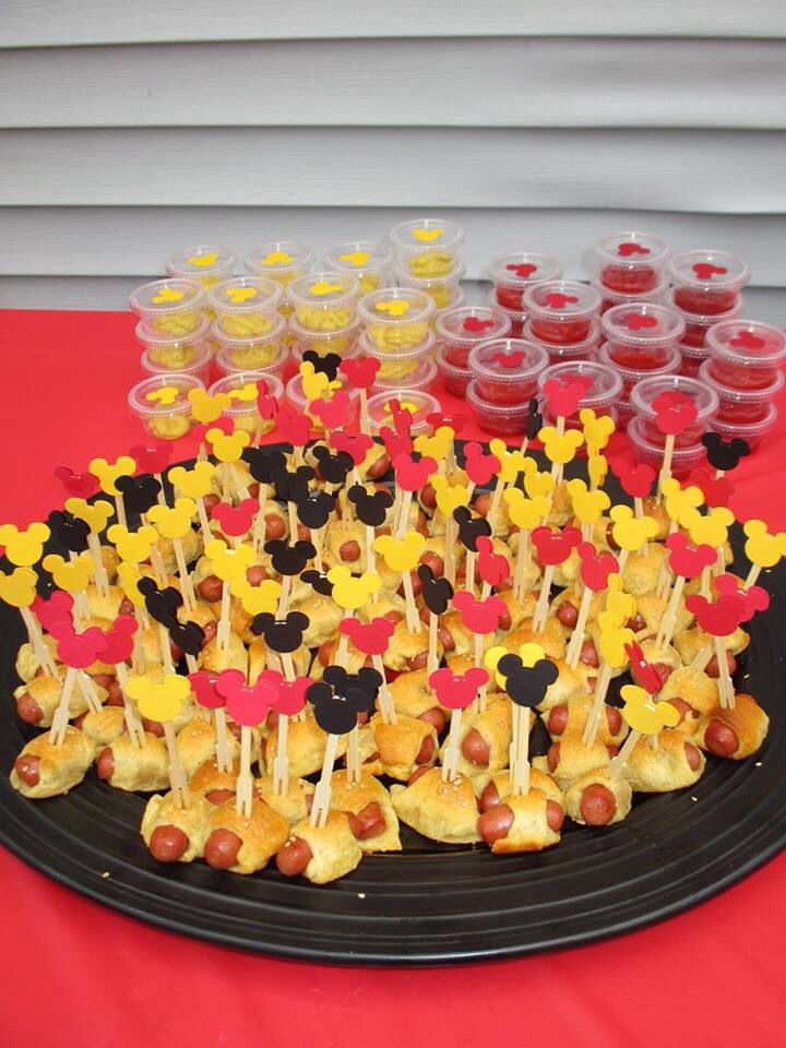 mickey mouse cupcakes are arranged on a black plate with red and yellow cups