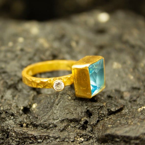 Blue Topaz Stone Ring | Silver Ring 24K Gold Plated | Ancient Art  Emerald Cut Ring | Birthstone  Jewelry | Hammered  Dainty Gift Our shop offer free ring sizingHandcrafted hammered  ring Metal : 925 Sterling SilverPlating : 24K GoldBand Width : 3 mmGem Stone : Lab created Topaz Stone / TopazGem Size : 9 X 9 mm / 3 mmRing Weight : 4 gramsRing Size : US 6 (The size you want is made for free).(We used the US standard sizing) **Custom Orders is Made**As pellada family, we will be happy to help you Gold Rings With Topaz Gemstone Accents, Gold Fusion Rings With Gemstone Accents, Gold Blue Topaz Ring For Gift, Handmade Gold Topaz Promise Ring, Gold Topaz Ring With Gemstone Accents, Gold Blue Topaz Ring With Bezel Setting, Unique Gold Ring With Blue Topaz, Handmade Yellow Gold Topaz Ring Gift, Gold Topaz Ring With Accent Stones For Gift