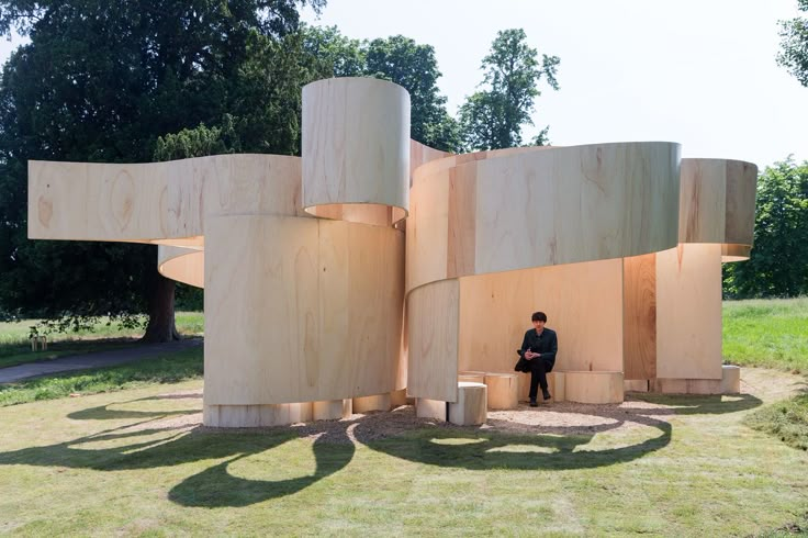 a person sitting on a bench in front of a sculpture