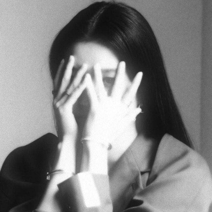 a black and white photo of a woman holding her hands up to her face with both hands