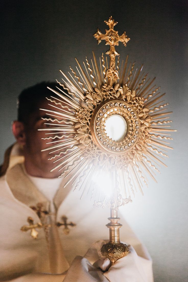 the priest is holding his cross in front of him and looking at it with light shining through