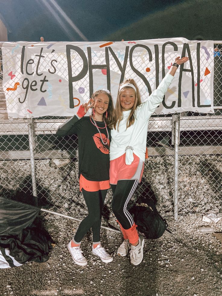 two girls standing next to each other in front of a sign that says let's get physical